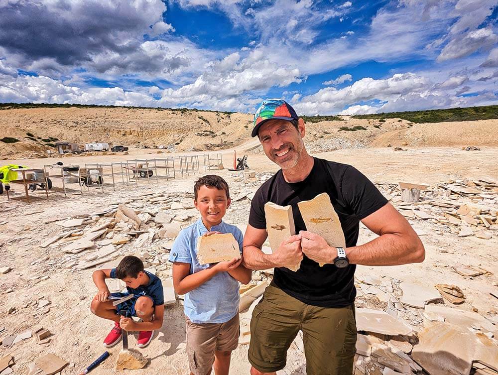 A father and son proudly hold up their finds at the American Fossil Quarry, as their son/brother uses a tool to hunt for more fossils in Kemmerer.