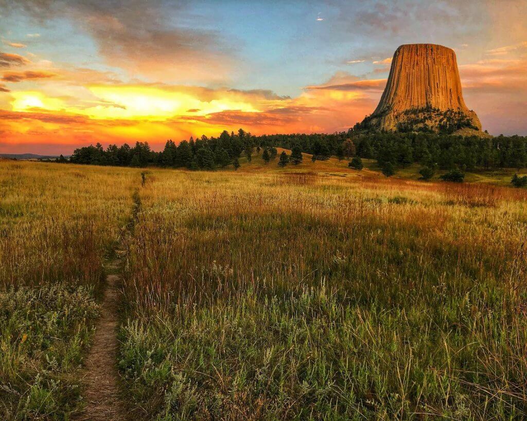 A sunset blazes in the sky over the field atop Devils Tower National Monument.