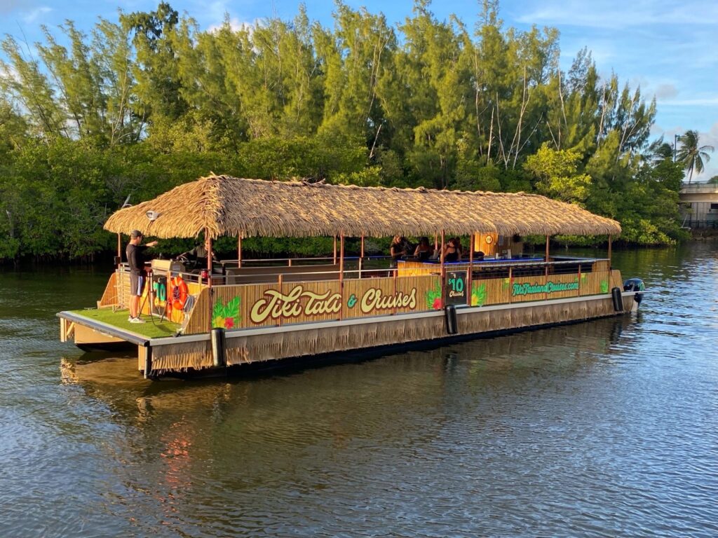 A photo of the Tiki Taxi pontoon boat cruising on the water with people aboard.